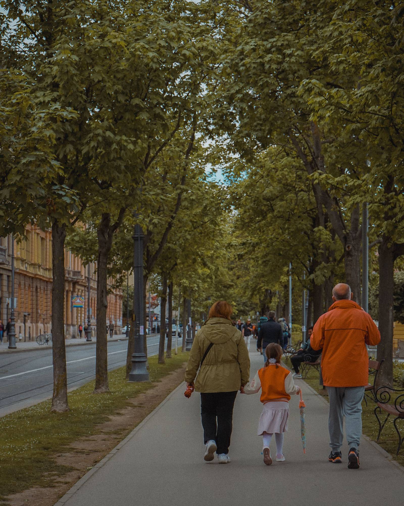 A family walking along a tree-lined street in Budapest